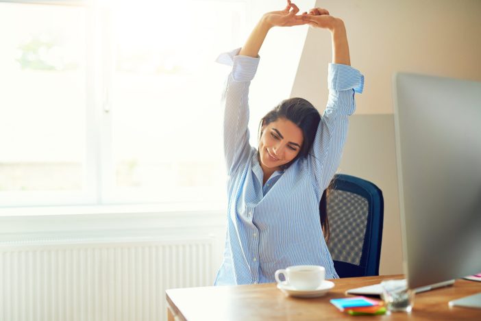 Image of woman stretching at desk