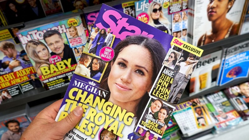 A hand holds a copy of Star magazine up with a cover photo of Meghan Markle