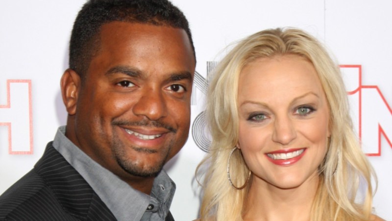 Alfonso Ribeiro wears a dark suit as he poses with his wife, Angela Unkrich, on the red carpet