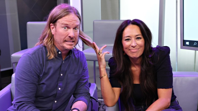 Chip Gaines playfully grimaces as his wife Joanna holds up a lock of his long hair