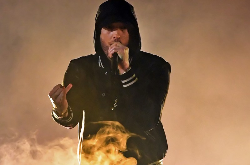 Eminem performing on stage behind flames.