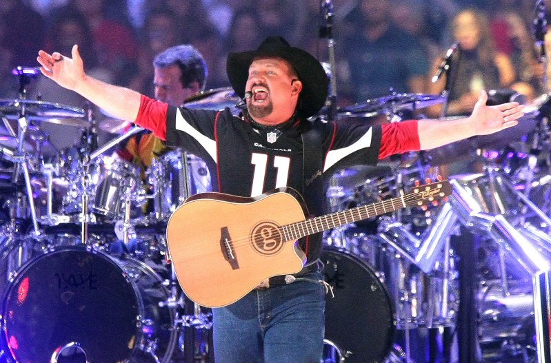 Garth Brooks performing on stage at a stadium concert.