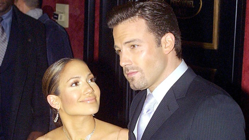 Jennifer Lopez gazes up at Ben Affleck, in a dark suit, on the red carpet