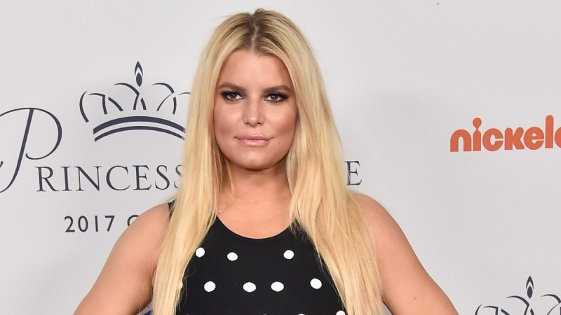 Jessica Simpson wears a black dress with white spots in front of a white background
