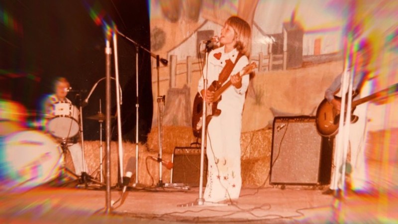 A childhood photo of Keith Urban, in a white jumpsuit, performing onstage