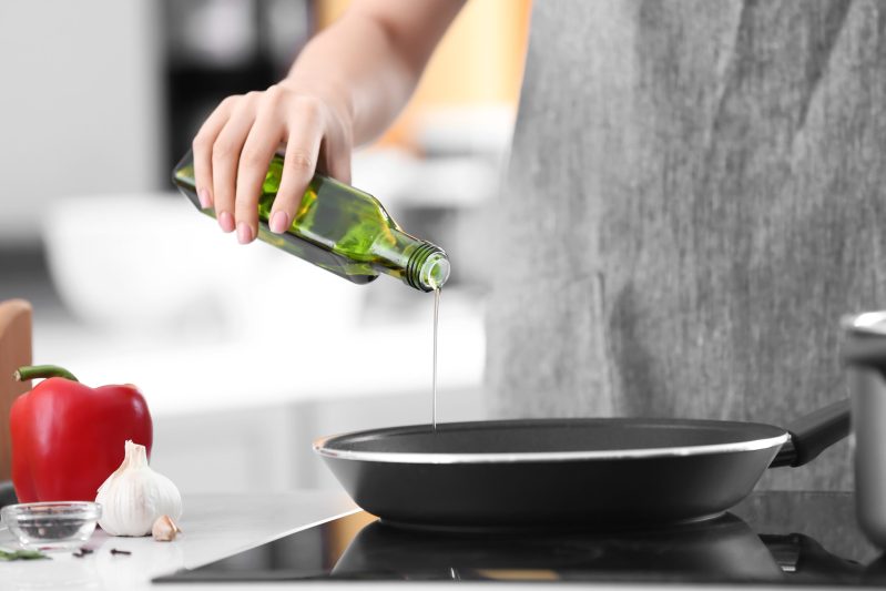 Image of woman cooking with olive oil.