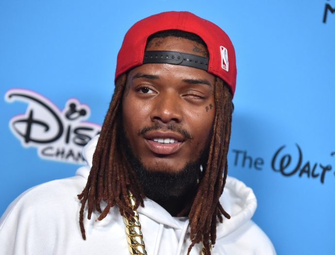 Fetty Wap at a rep carpet event with a backwards red hat, white hoodie, and gold chain.