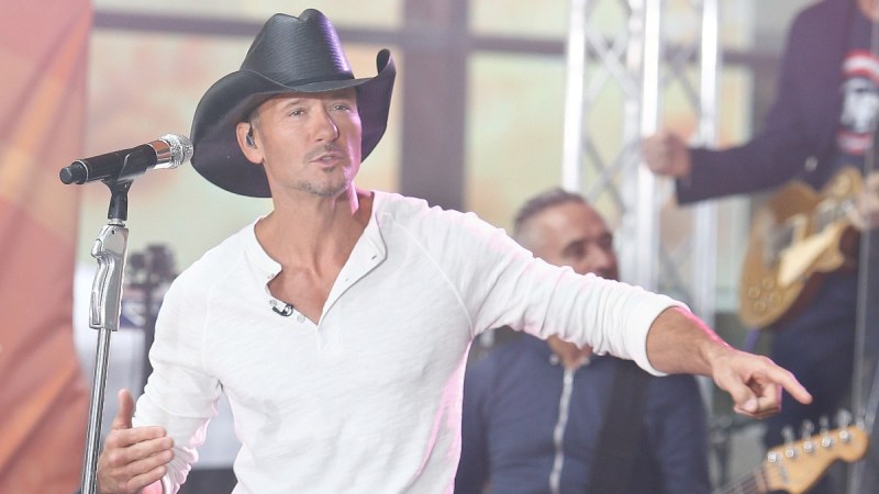 Tim McGraw wears a white shirt on stage as he performs in a black cowboy hat