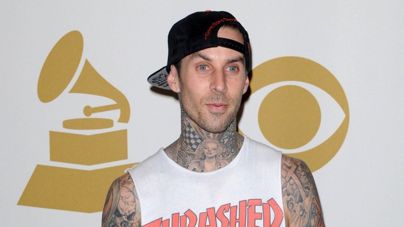 Travis Barker wears a white shirt and black baseball hat on the red carpet