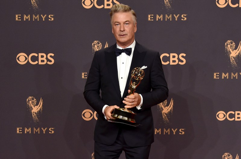 Alec Baldwin holding an Emmy award.