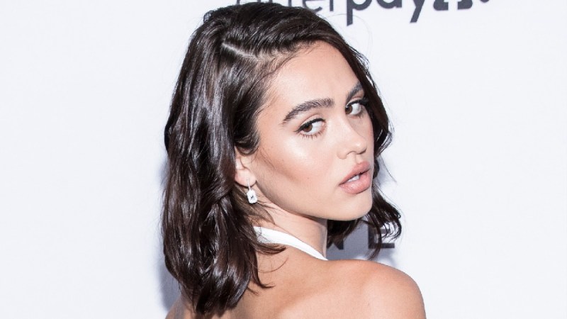 Amelia Hamlin wears a white dress and looks over her shoulder on the red carpet
