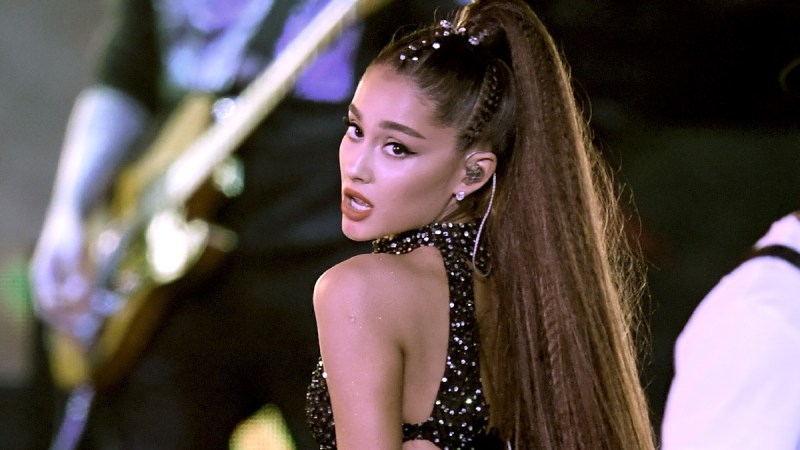 Ariana Grande looks over her shoulder in a black dress onstage