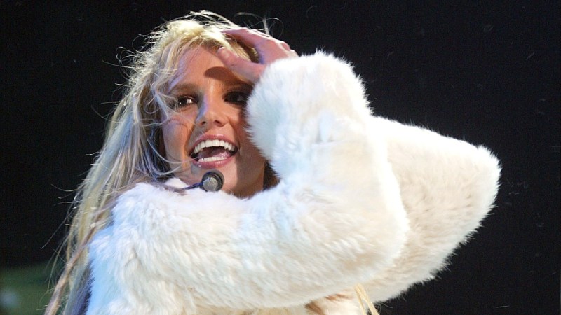 Britney Spears wears a white fuzzy jacket onstage