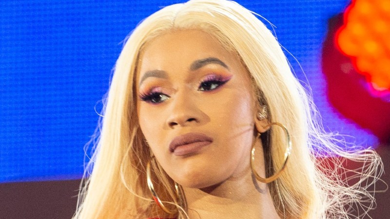 Cardi B performs onstage against a blue backdrop dressed in all red