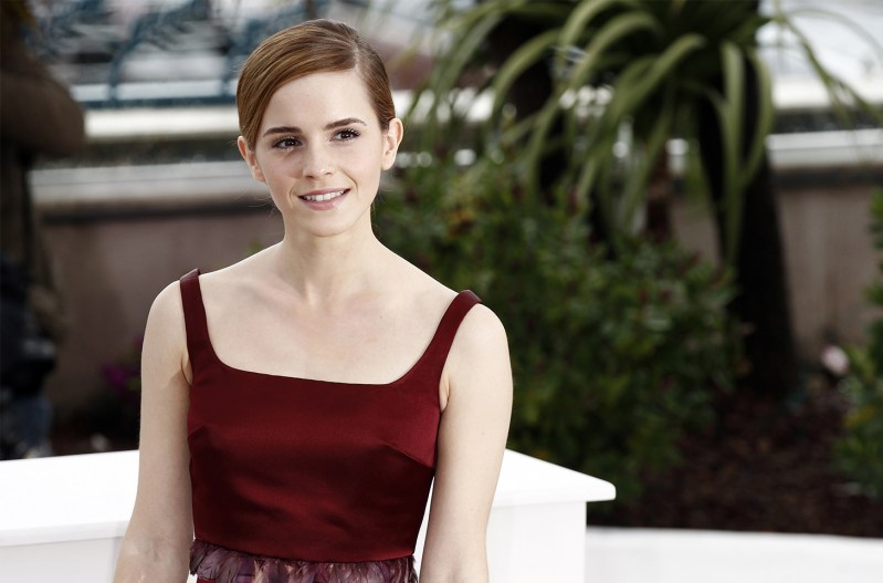 Emma Watson smiling in a red dress, sitting on a white chair