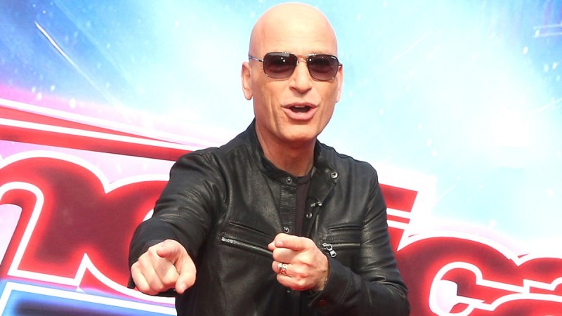 Howie Mandel wears a black leather jacket and points on the red carpet