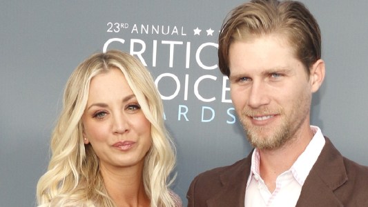 Kaley Cuoco and Karl Cook pose together on the red carpet against a gray background