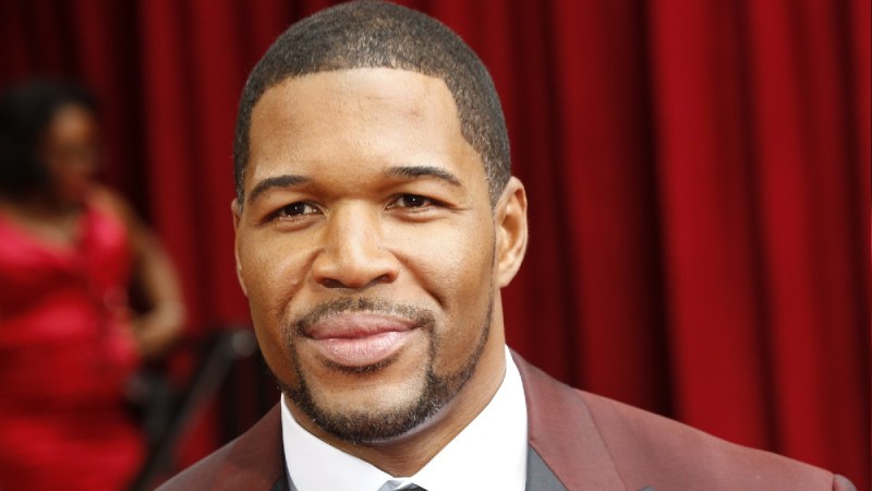 Michael Strahan wears a dark red suit on the red carpet
