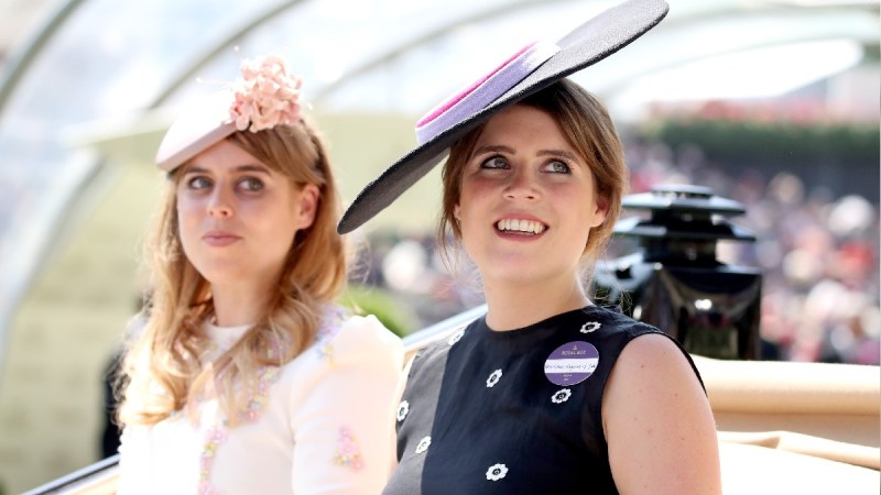 Princess Beatrice, in pink, rides with Princess Eugenie, in dark colors, in a carriage