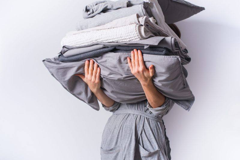 Image of woman holding piles of laundry.