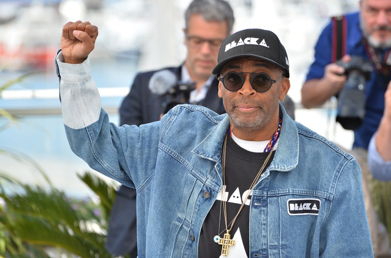 Spike Lee holding his right fist up in the air.
