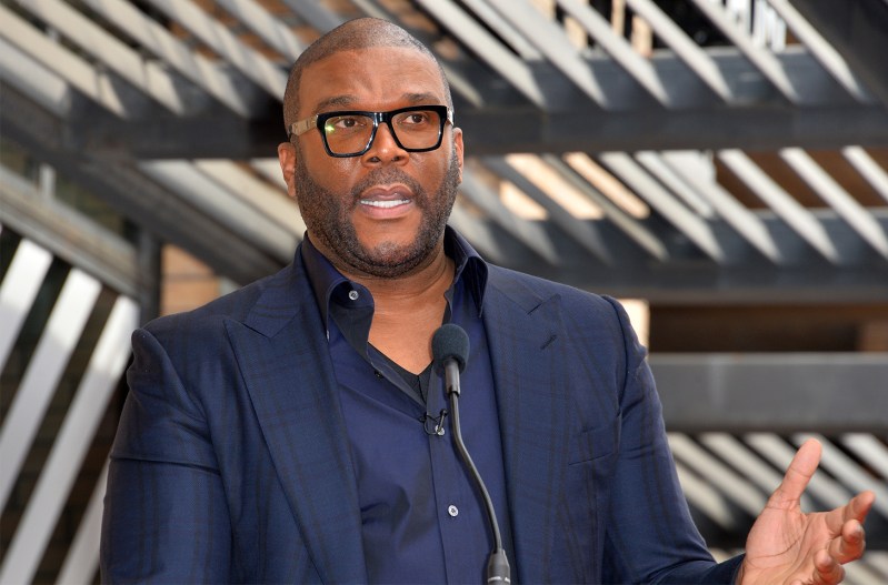Tyler Perry in a suit, speaking into a microphone