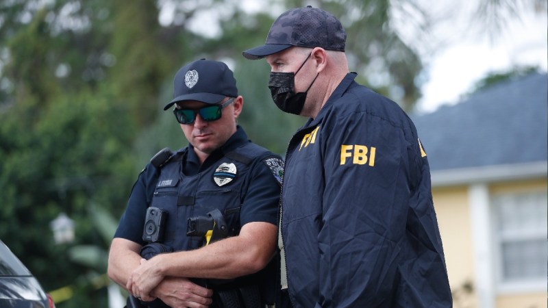 Two officers, one wearing an FBI jacket, stand outside of Brian Laundrie's home in Florida