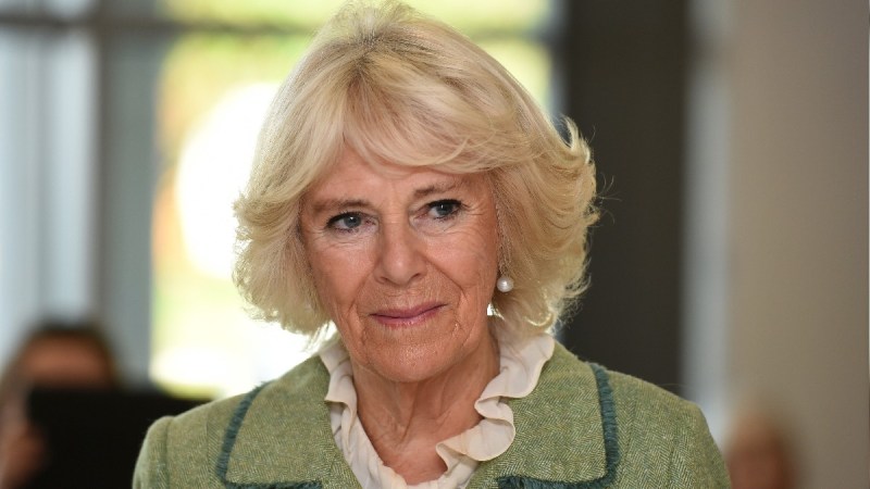 Camilla Parker Bowles wears a green coat over a white blouse at a hospital event