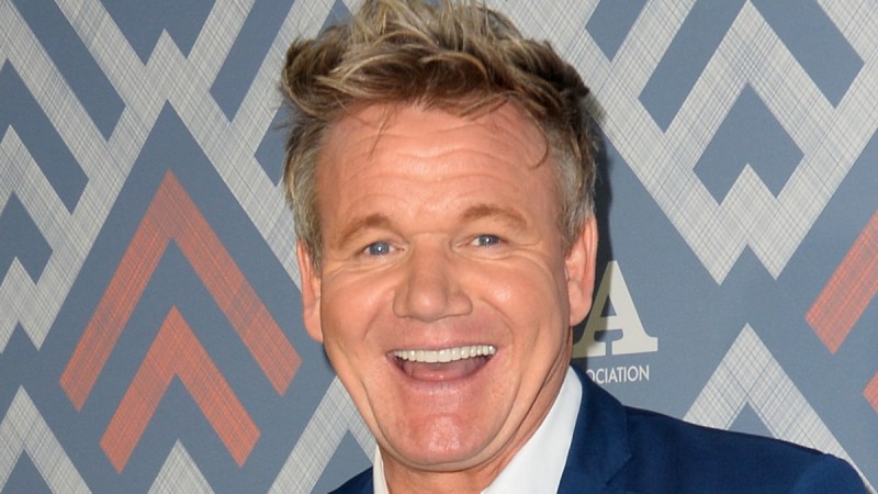 Gordon Ramsay laughs while wearing a blue suit on the red carpet