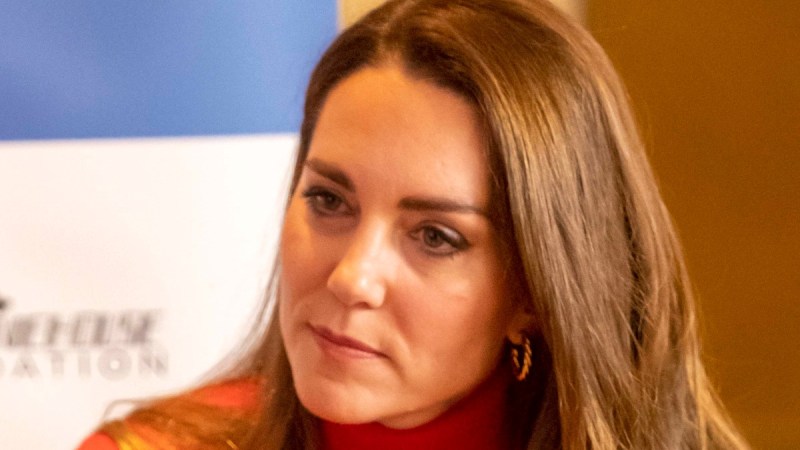 Kate Middleton listens intensely while wearing a red dress