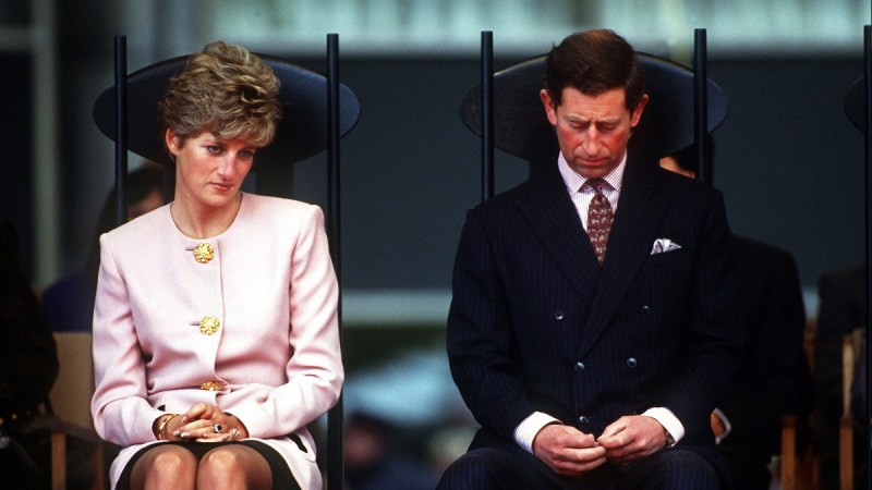 Princess Diana, in pink, sits beside Prince Charles, in a dark suit