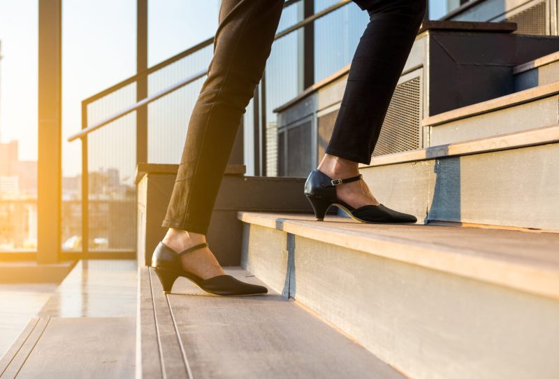 Woman wearing low heels walking up a flight of stairs.