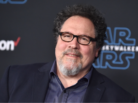 Jon Favreau wearing black glasses and a dark blue suit
