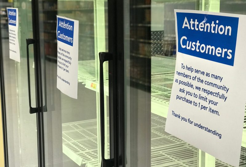 Empty freezer in grocery store with note to customers to limit purchases.