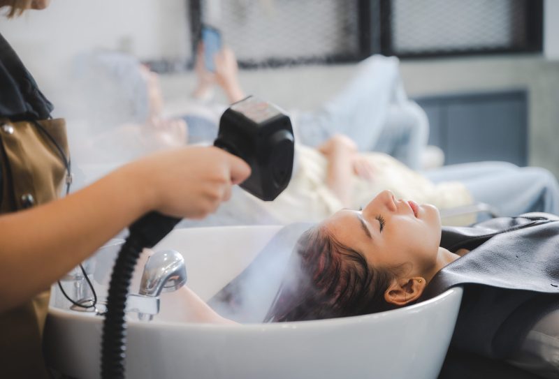 Woman getting her hair steamed at a salon.
