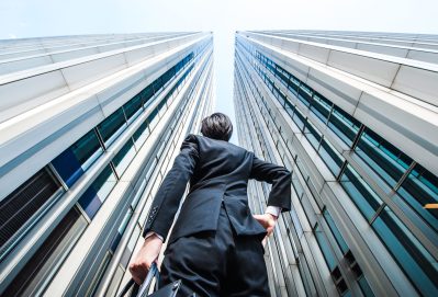 Businessman looking up at tall office buildings.