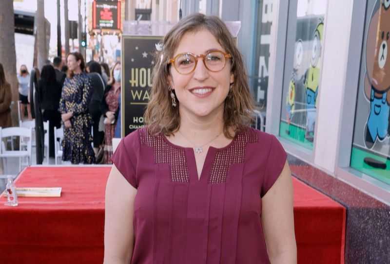Mayim Bialik smiling in a red blouse