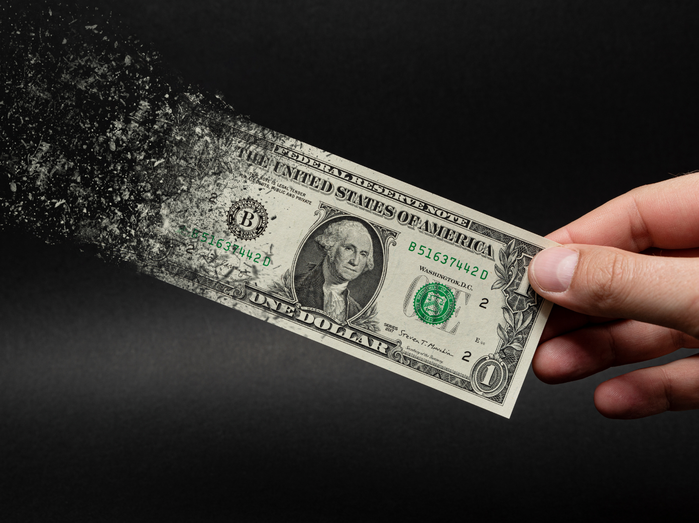 Hand holding onto a dollar bill as it dissolves