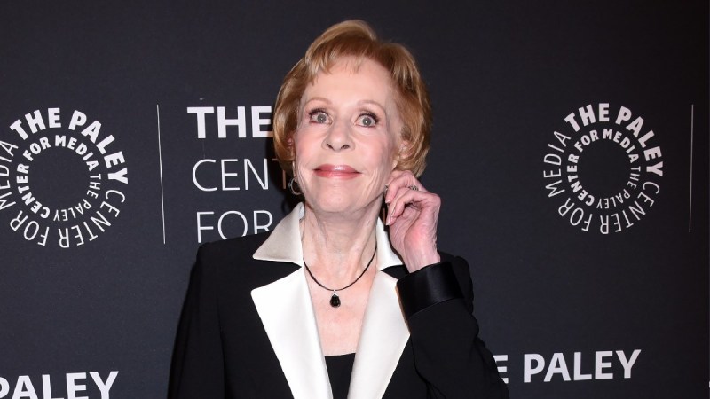 Carol Burnett wears a dark jacket over a black dress on the red carpet