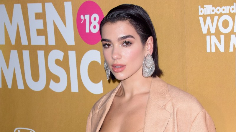 Dua Lipa wears a beige jacket over a matching top on the red carpet