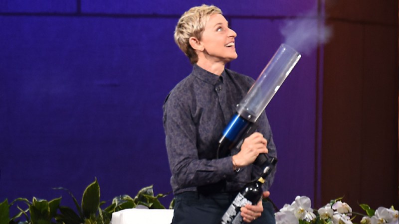 Ellen DeGeneres wears a dark top and pants and shoots a t-shirt cannon into the crowd