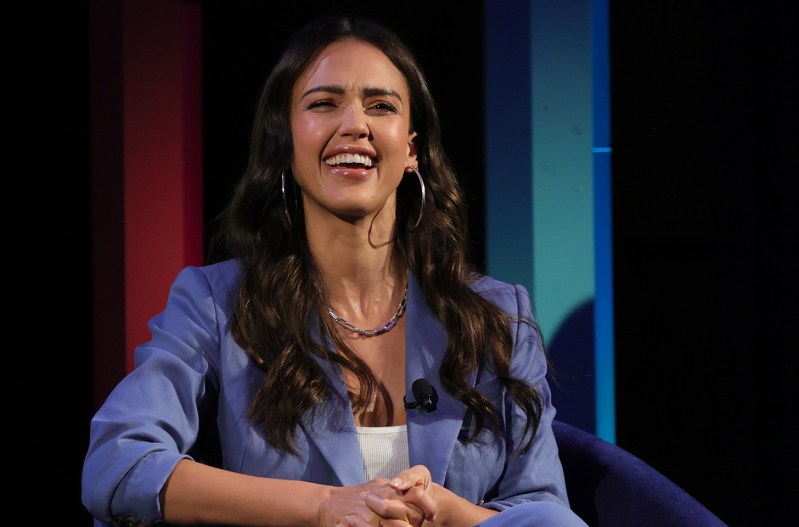 Jessica Alba sitting in a chair on a stage, laughing
