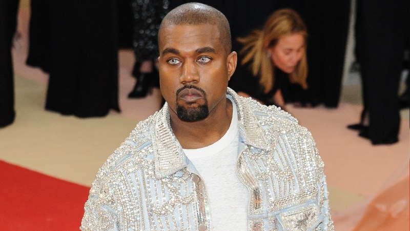 Kanye West wears a white shirt under a silver bejeweled jacket on the Met Gala red carpet