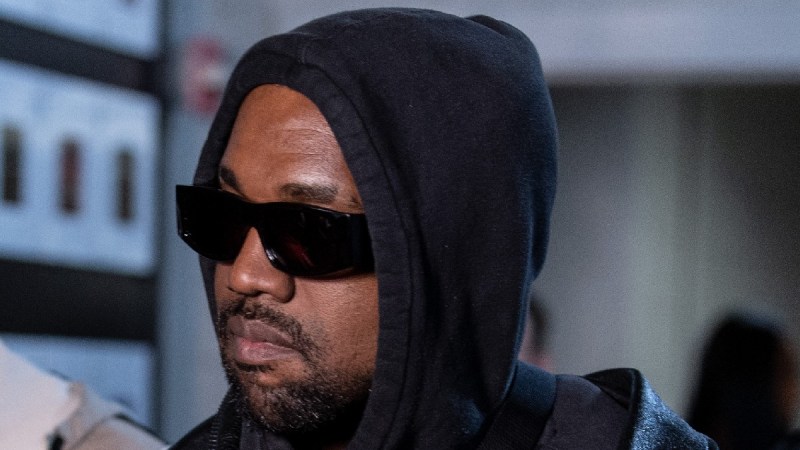 Kanye West wears black sunglasses and a black hoodie indoors in Atlanta