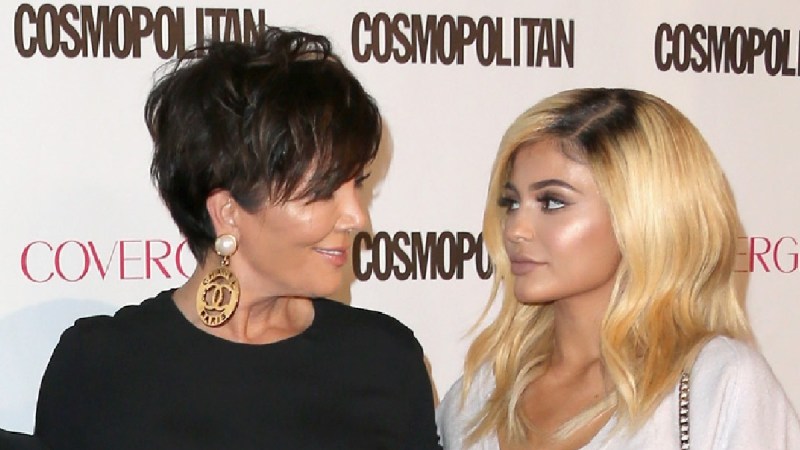 Kris Jenner, in black, shares a look with daughter Kylie, in white, on the red carpet