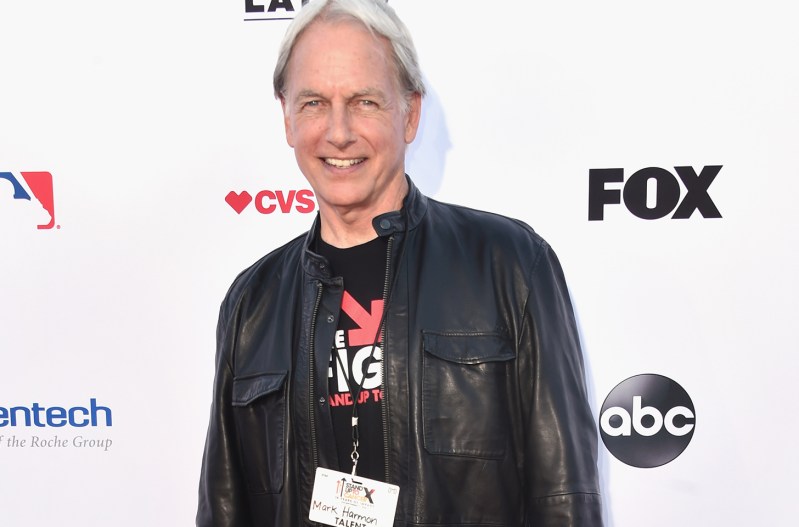 Mark Harmon smiling in a black leather jacket at a charity event.