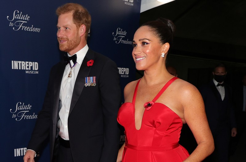 Prince Harry on the left in a tux, Meghan Markle on the right in a red dress.