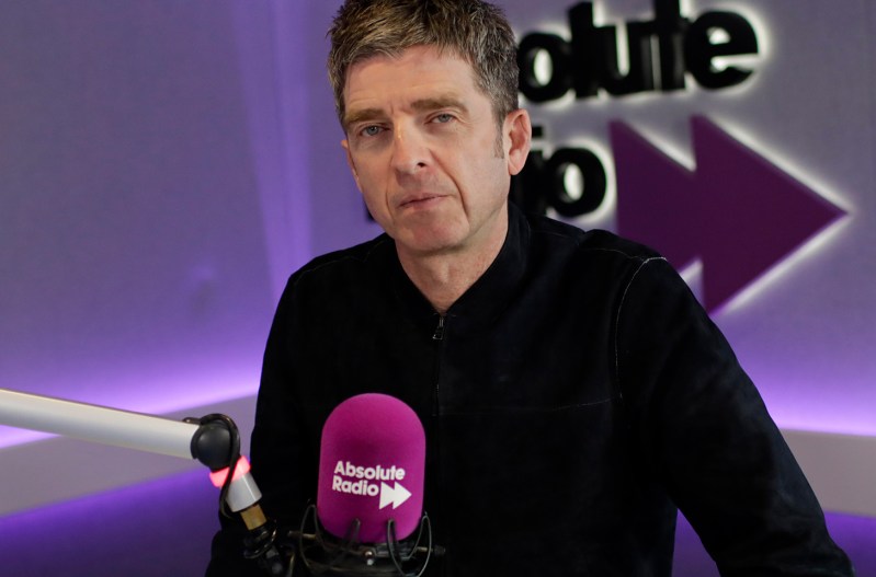 Noel Gallagher at a microphone doing a radio appearance