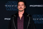 Pedro Pascal at a Star Wars event in a purple shirt and black jacket with white piping