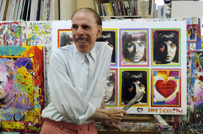 Peter Max posing with some of his artwork of The Beatles
